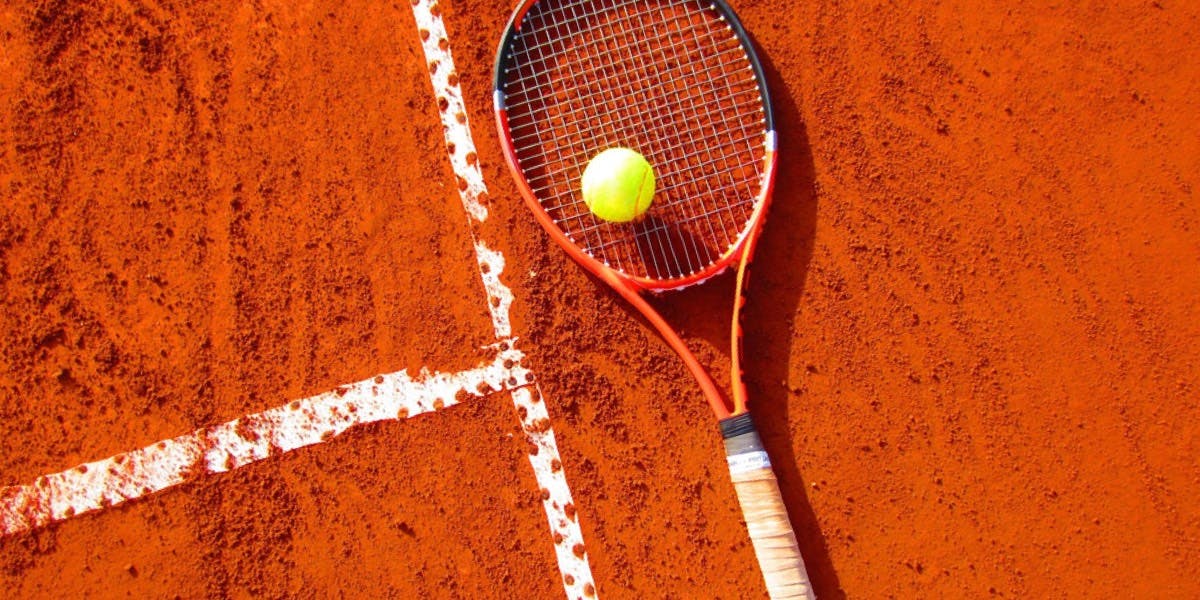 A tennis racquet on a clay court