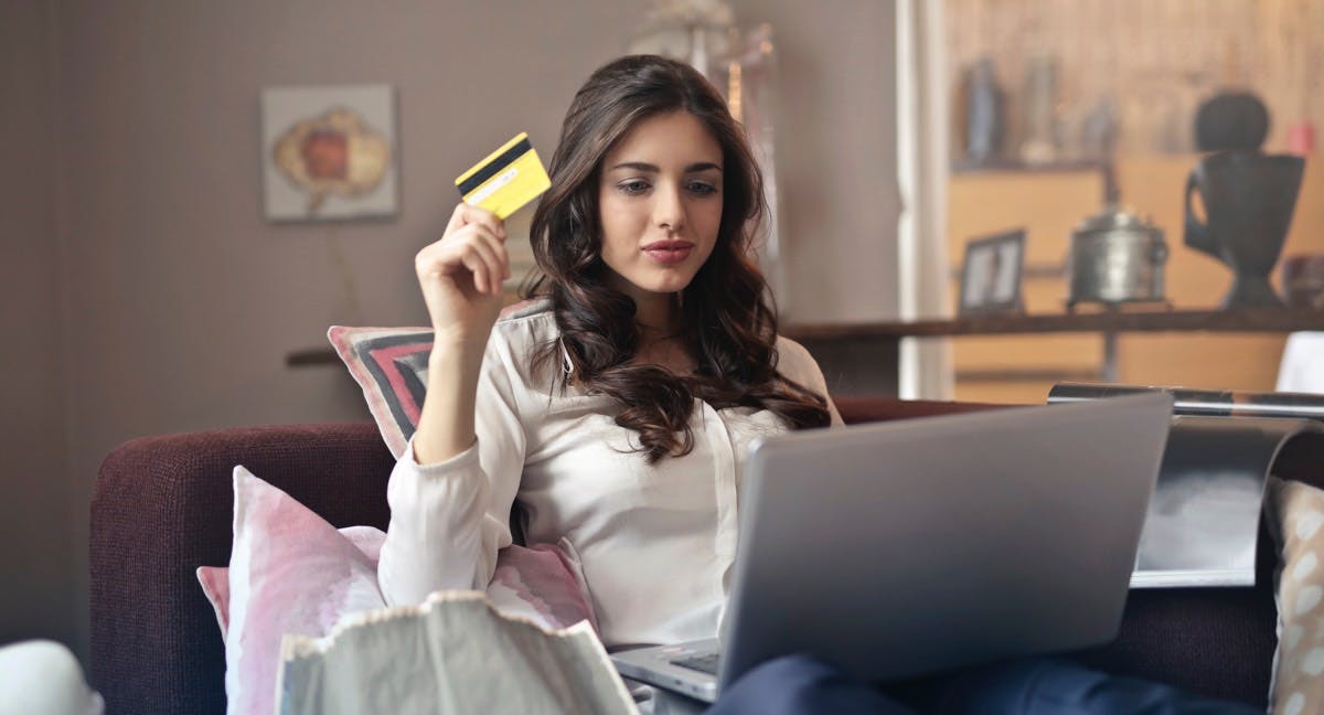 A woman holding a credit card in front of a computer